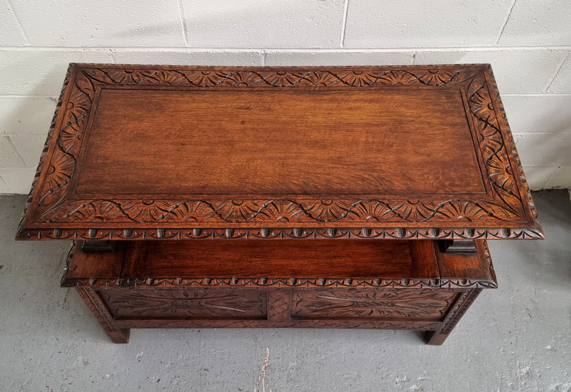 Unusual English Oak Monks Bench.  The tabletop is set onto a lift top chest in such a way that when the table is not in use, the top pivots to a vertical position and becomes the back of a Settle. Carved Lion table rests and carving to front.  In good, detailed condition.