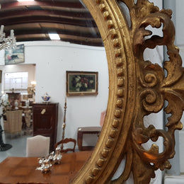 Large round carved wooden convex mirror. Still contains its original mirror which shows signs of aging.