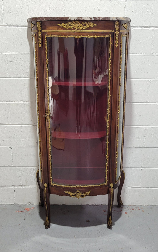 Louis XV style Vitrine with curved glass and red velvet lining. It has two fixed shelves with a marble top and ormolu decoration. In good original detailed condition.