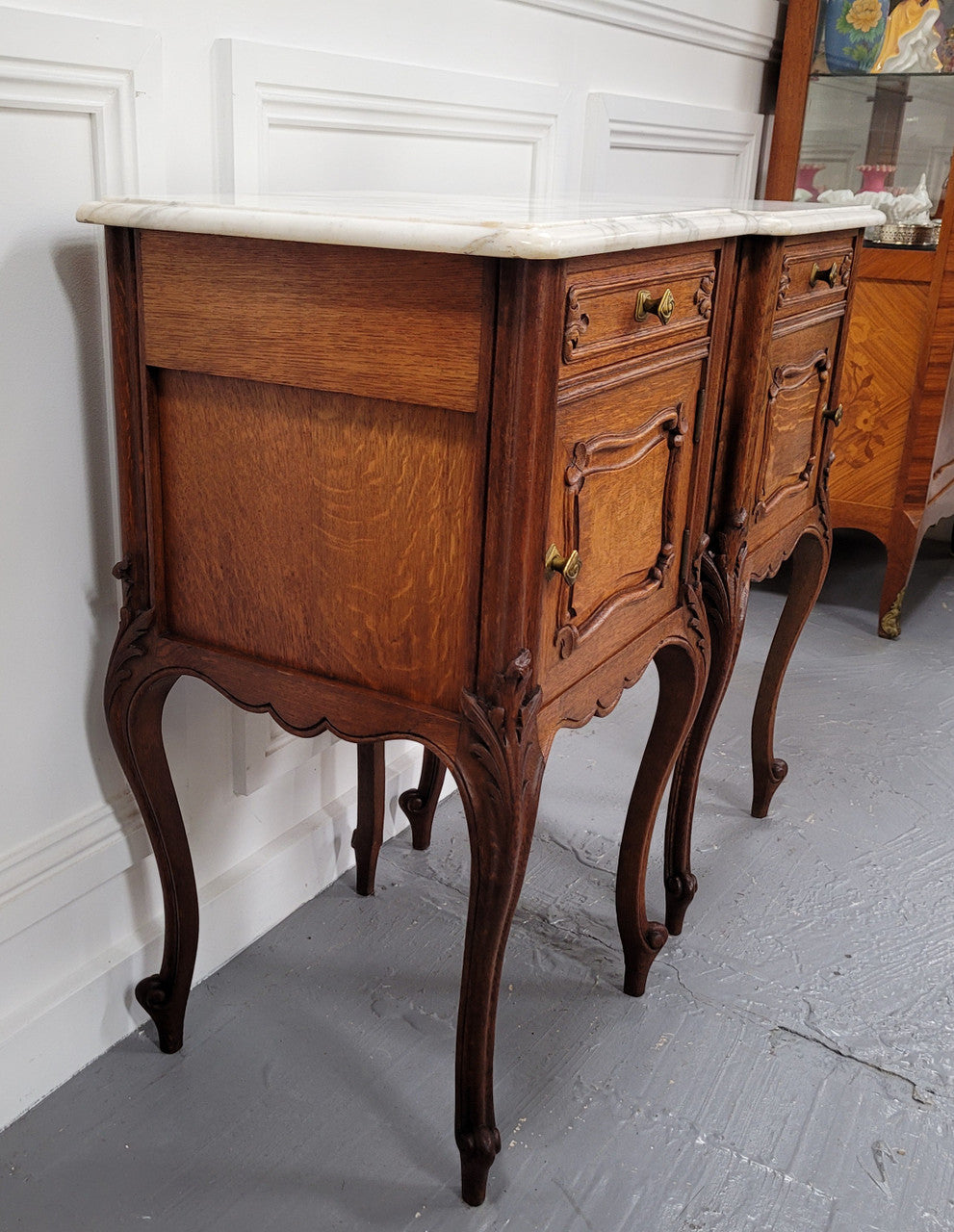 Pair of French Antique Louis XV style Oak marble top night stands. They have beautiful carved cabriole legs and beautiful white marble along with a drawer and cupboard for storage space. They have been sourced from France and are in good original detailed condition.