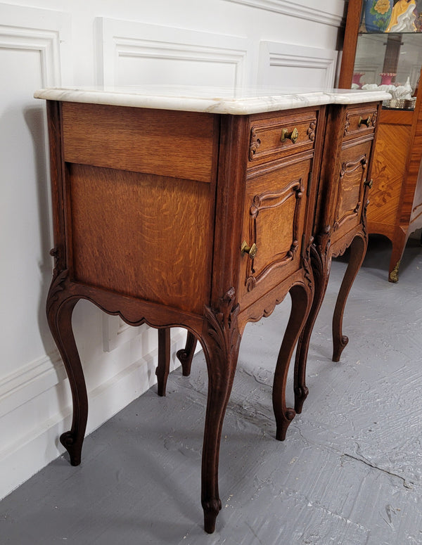 Pair of French Antique Louis XV style Oak marble top night stands. They have beautiful carved cabriole legs and beautiful white marble along with a drawer and cupboard for storage space. They have been sourced from France and are in good original detailed condition.