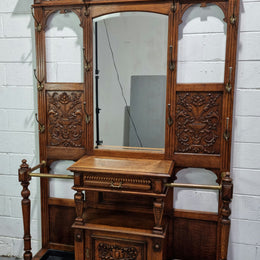 Grand Henry 2nd Style French Oak hall stand with 12 hanging hooks. Also has one cupboard and drawer for storage along with a mirror and two areas either side for umbrellas and walking sticks. In good original detailed condition.