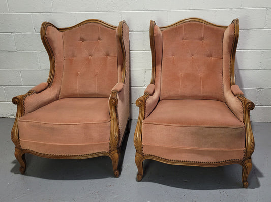 French pair of  Walnut Louis XV style pink upholstered wing back chairs. They are very comfortable to sit in and are of generous portions. The fabric is in good original condition and does have stains and would ideally be reupholstered.