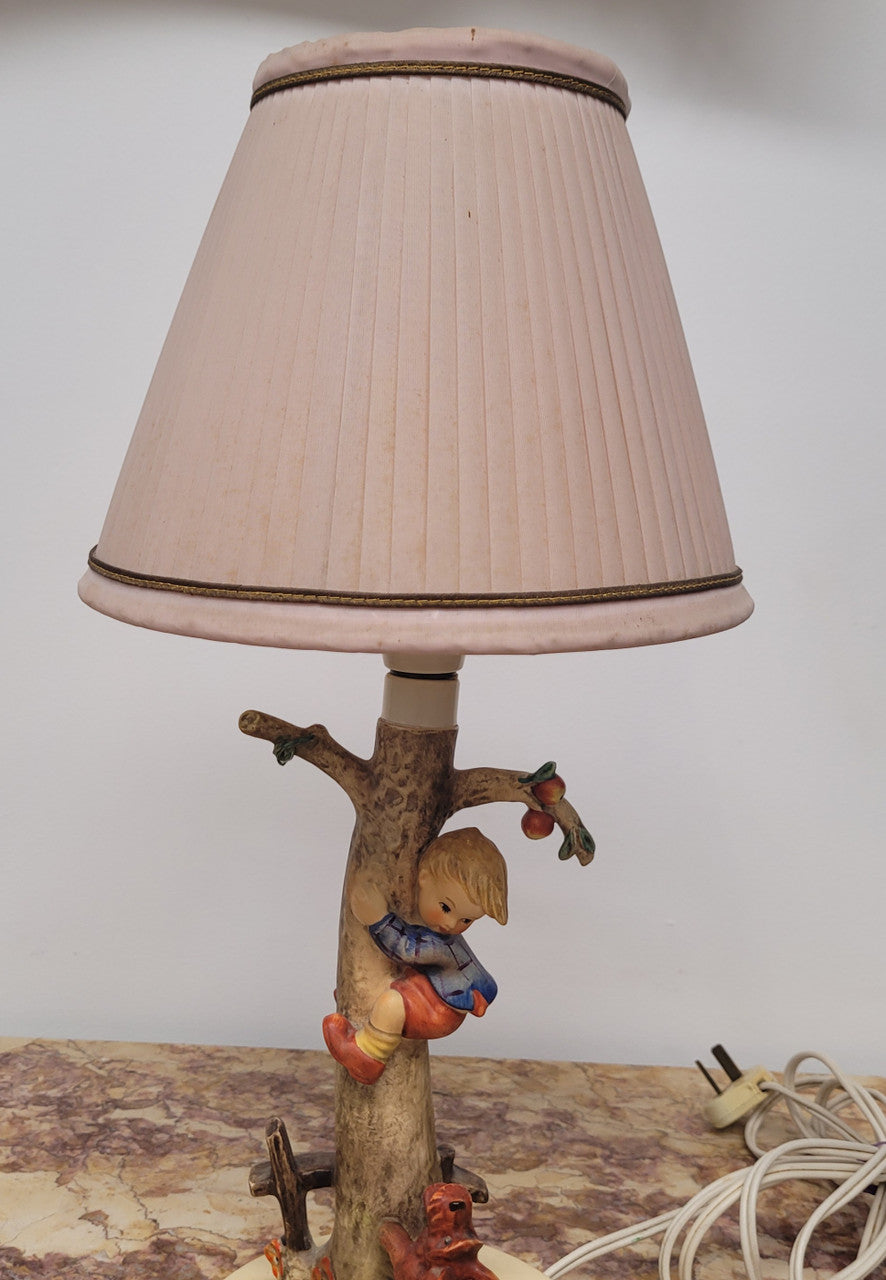 Charming Hummel Lamp featuring a young boy climbing an apple tree with a barking dog on the ground.  Incised Hummel mark on side of base and 44A on base with 1935 (copyright) and Goebel W Germany. Height without shade 33.5cm