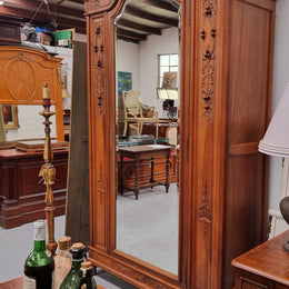 Imposing Louis XV style single mirrored door Walnut armoire. Features deep carved decoration, two interior drawers and three adjustable shelves. It is in good original detailed condition and has been sourced from France.