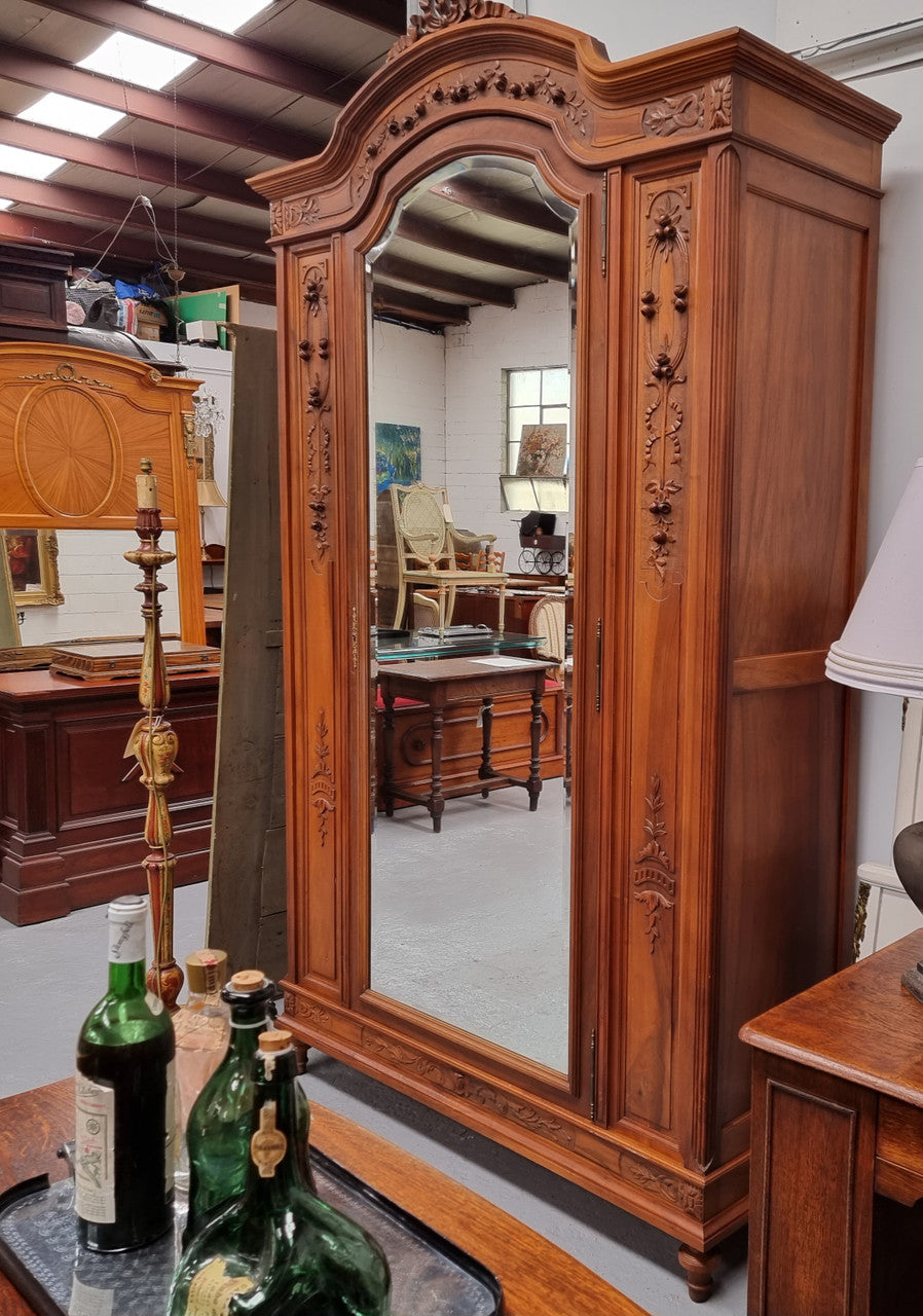 Imposing Louis XV style single mirrored door Walnut armoire. Features deep carved decoration, two interior drawers and three adjustable shelves. It is in good original detailed condition and has been sourced from France.