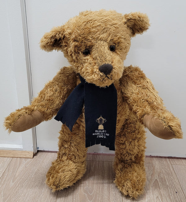 World Cup Rugby Bear. William by RUSS a special release for 2003. Limited to 5000 pieces worldwide. 50.8 cm fully jointed golden-brown bear with suedeen paw pads and blue scarf with Rugby World Cup Logo embroidery.

*Please note chair in photo is not included.