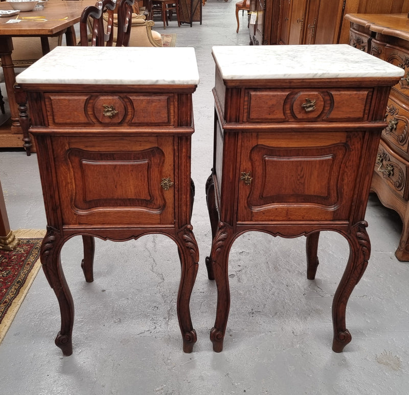 Elegant French Louis XV style pair of carved Oak white marble top bedsides. They are in good original condition and they have been detailed to a high standard. They have been sourced from France.