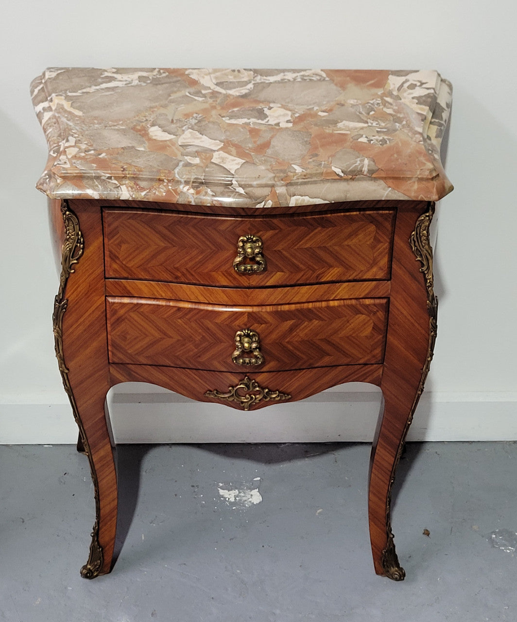 Pair of Louis XV commode style two drawer bedsides with beautiful marble tops and decorative mounts. They are a rare size and are in good, detailed condition.