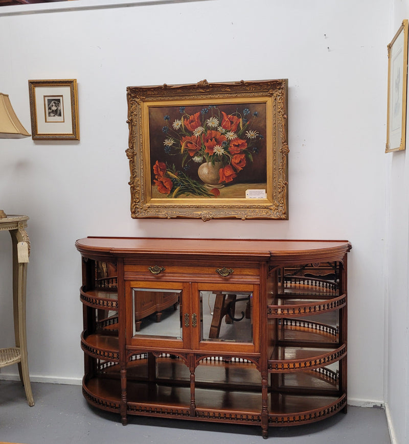A high quality Antique Walnut sideboard featuring two mirrored doors, two drawers and five open shelf areas with mirror backing. It is in good original detailed condition.