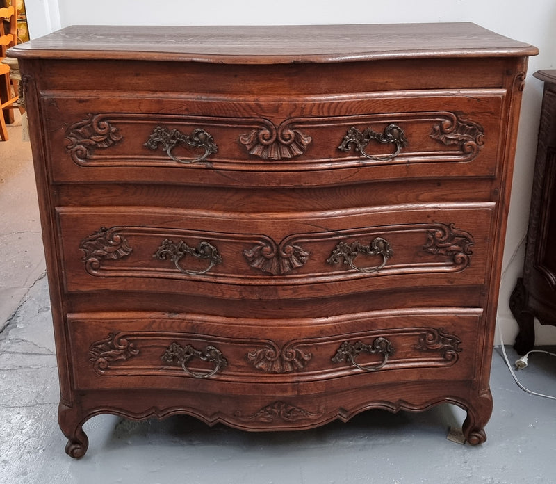 Antique French beautifully carved dark Oak commode with three drawers and ornate handles. It is in good original detailed condition.