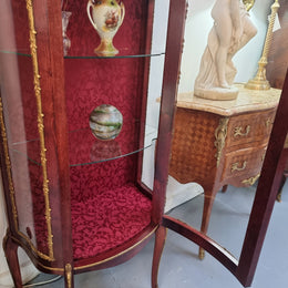 French Mahogany two shelf vitrine with curved glass and brass mounts. It has a lovely frabic interior and two glass shelves. In good original detailed condition.