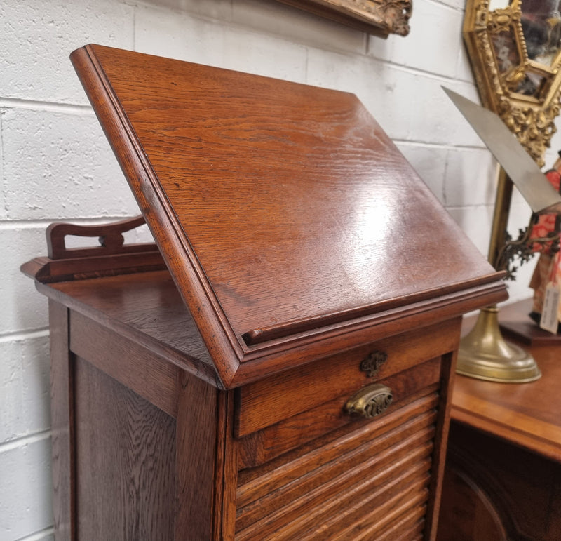 Antique Edwardian roll top Tambour file cabinet desk. This practical antique tambour front filing cabinet dates around 1900 in the Edwardian period and is constructed from Oak. This antique cabinet has an adjustable writing slope, above a tambour front with key and working lock. It has been sourced locally and is in good original detailed condition.