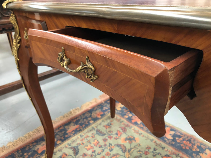 An impressive French Walnut petite Bureau Plat with superb ormolu mounts, original tooled leather top with loads of character and drawers for storage. It is in very good original detailed condition.