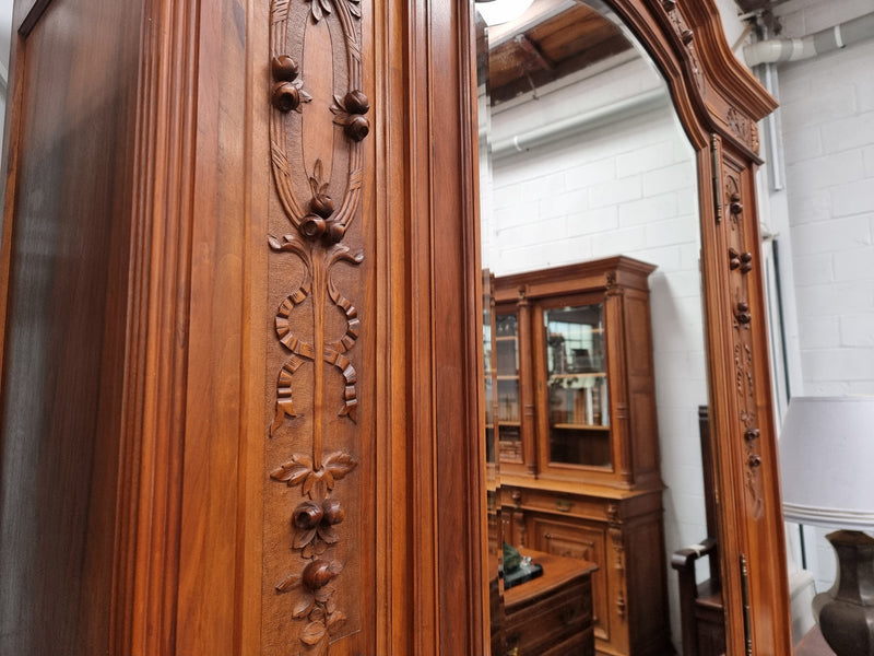 Imposing Louis XV style single mirrored door Walnut armoire. Features deep carved decoration, two interior drawers and three adjustable shelves. It is in good original detailed condition and has been sourced from France.