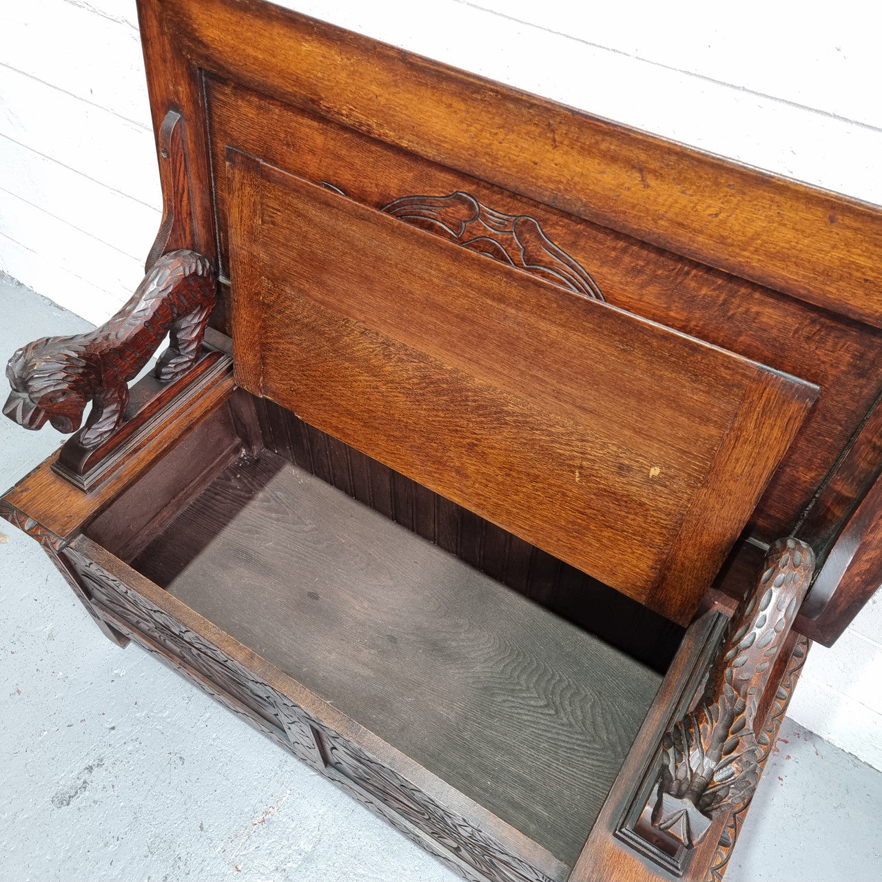 Unusual English Oak Monks Bench.  The tabletop is set onto a lift top chest in such a way that when the table is not in use, the top pivots to a vertical position and becomes the back of a Settle. Carved Lion table rests and carving to front.  In good, detailed condition.