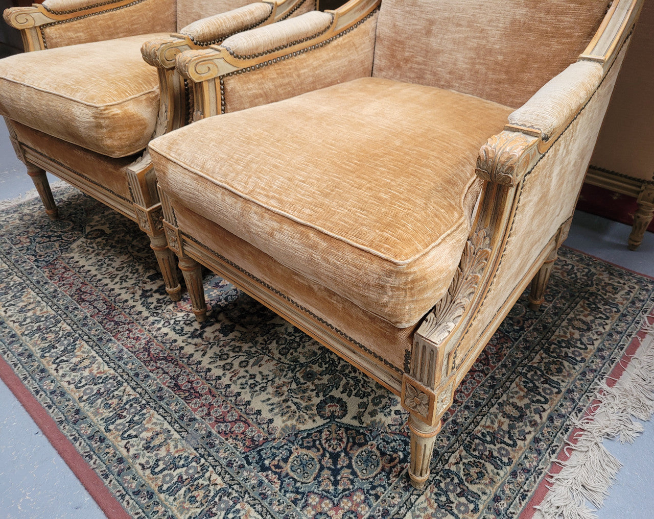 Pair of Louis XVI style painted arm chairs with carving & fluted legs. They have been sourced from France and the fabric is in good used original condition. Please view photos as they help form part of the description.