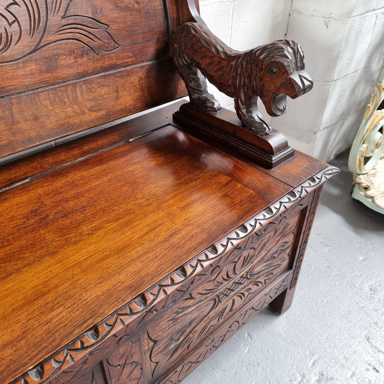 Unusual English Oak Monks Bench.  The tabletop is set onto a lift top chest in such a way that when the table is not in use, the top pivots to a vertical position and becomes the back of a Settle. Carved Lion table rests and carving to front.  In good, detailed condition.