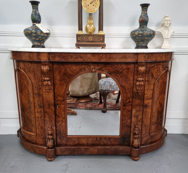 An elegant Antique Victorian Burr wood Walnut marble-top sideboard credenza with a mirrored center door. It has a white shaped marble top, mirror front, nicely carved details and three swing doors along with two keys. It is in good original detailed condition.