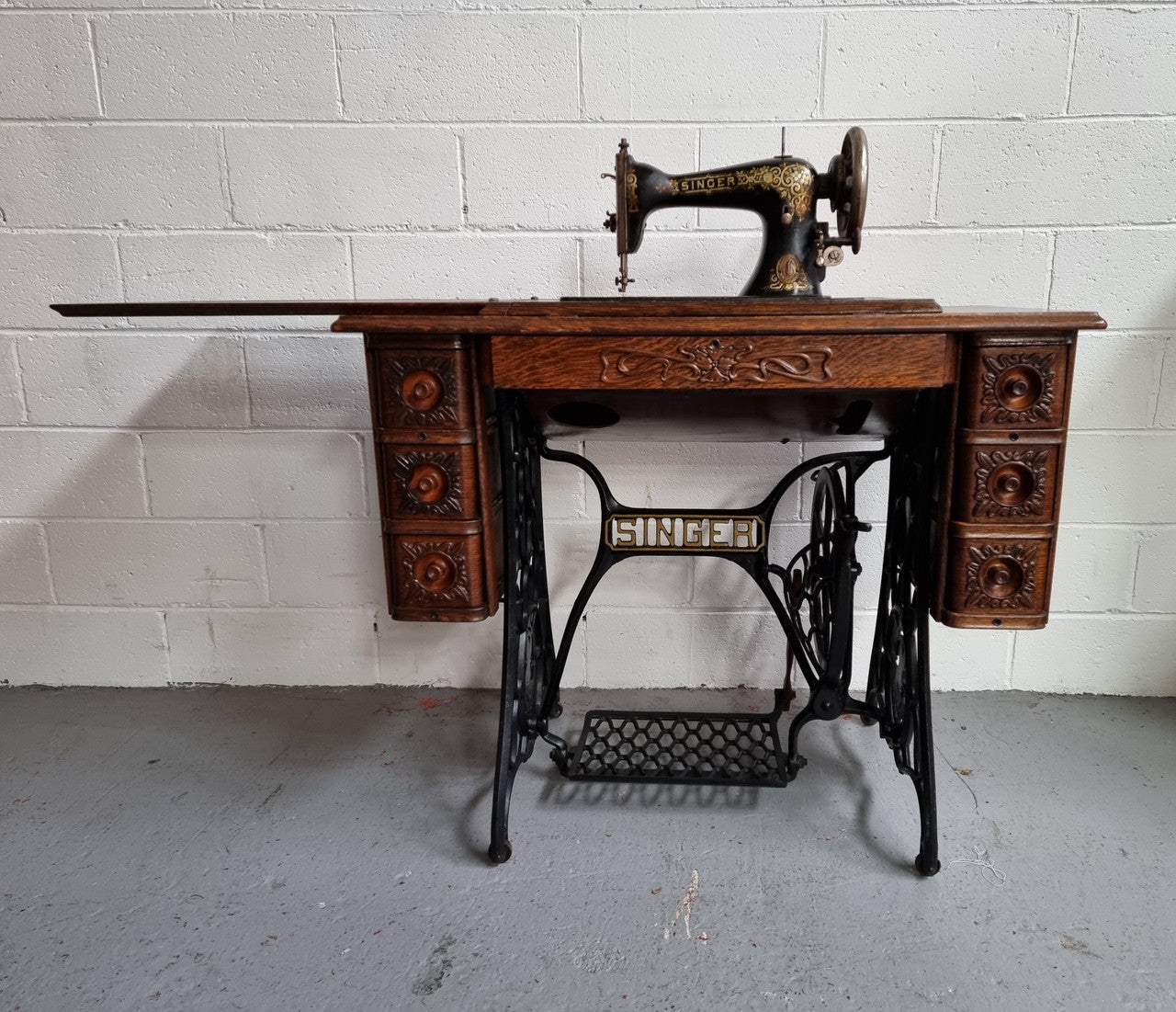 Singer Treadle sewing machine with six decorative side drawers and one centre drawer in Oak on cast iron base. It is in original condition.