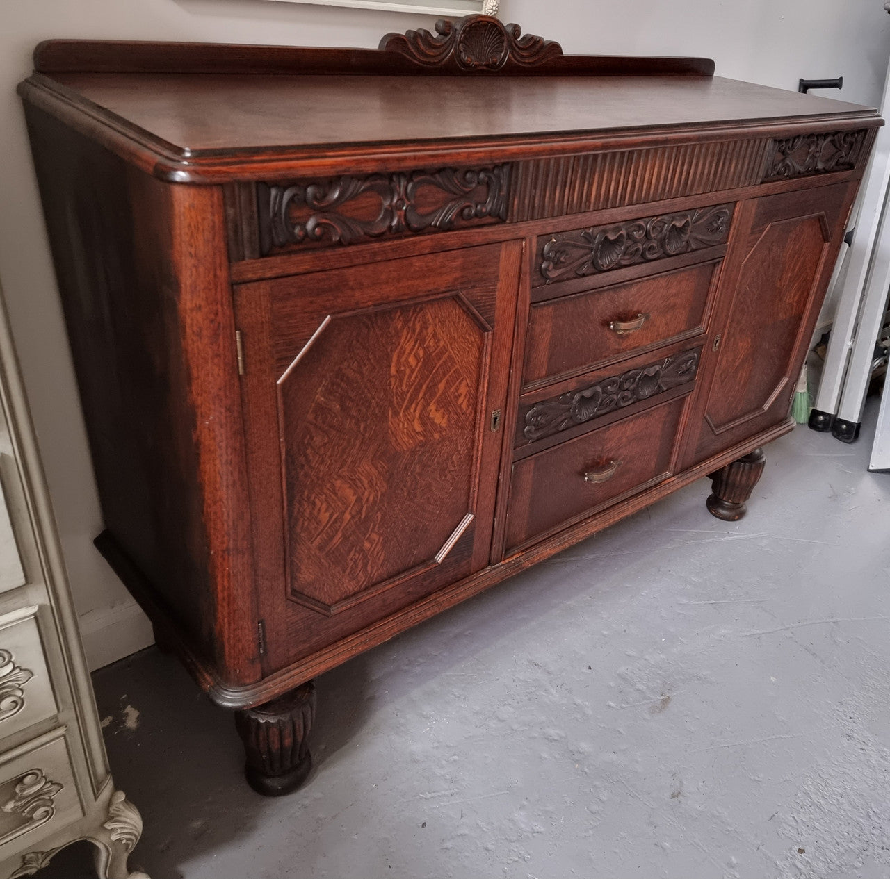 Art Deco Tudor style Oak sideboard with decorative carved detail. Plenty of storage space with two cupboards and four drawers. It has been sourced locally and is in good original detailed condition.
