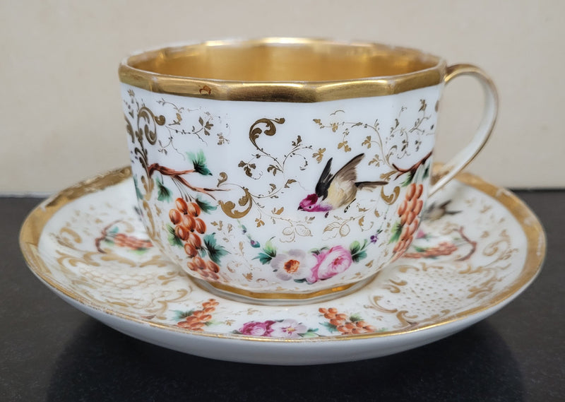 “Old Paris Porcelain” large cup and saucer, beautifully decorated with birds, grapes, floral sprays and heavily gilded. Dated to base 1835. In good original condition please view photos as they help form part of description.