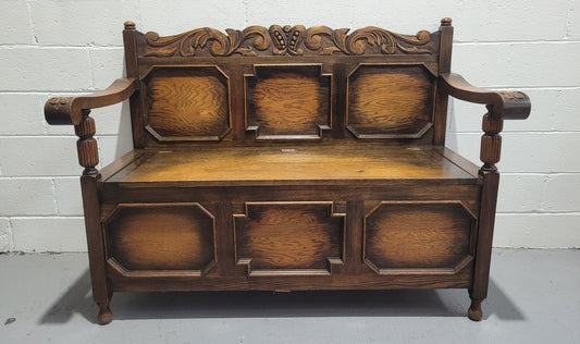 English Oak Tudor style hall seat with lift up top and a storage compartment underneath. It is in good original detailed condition with its original finish.