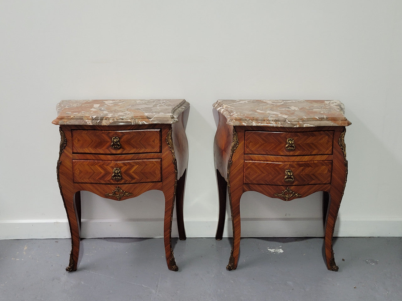 Pair of Louis XV commode style two drawer bedsides with beautiful marble tops and decorative mounts. They are a rare size and are in good, detailed condition.