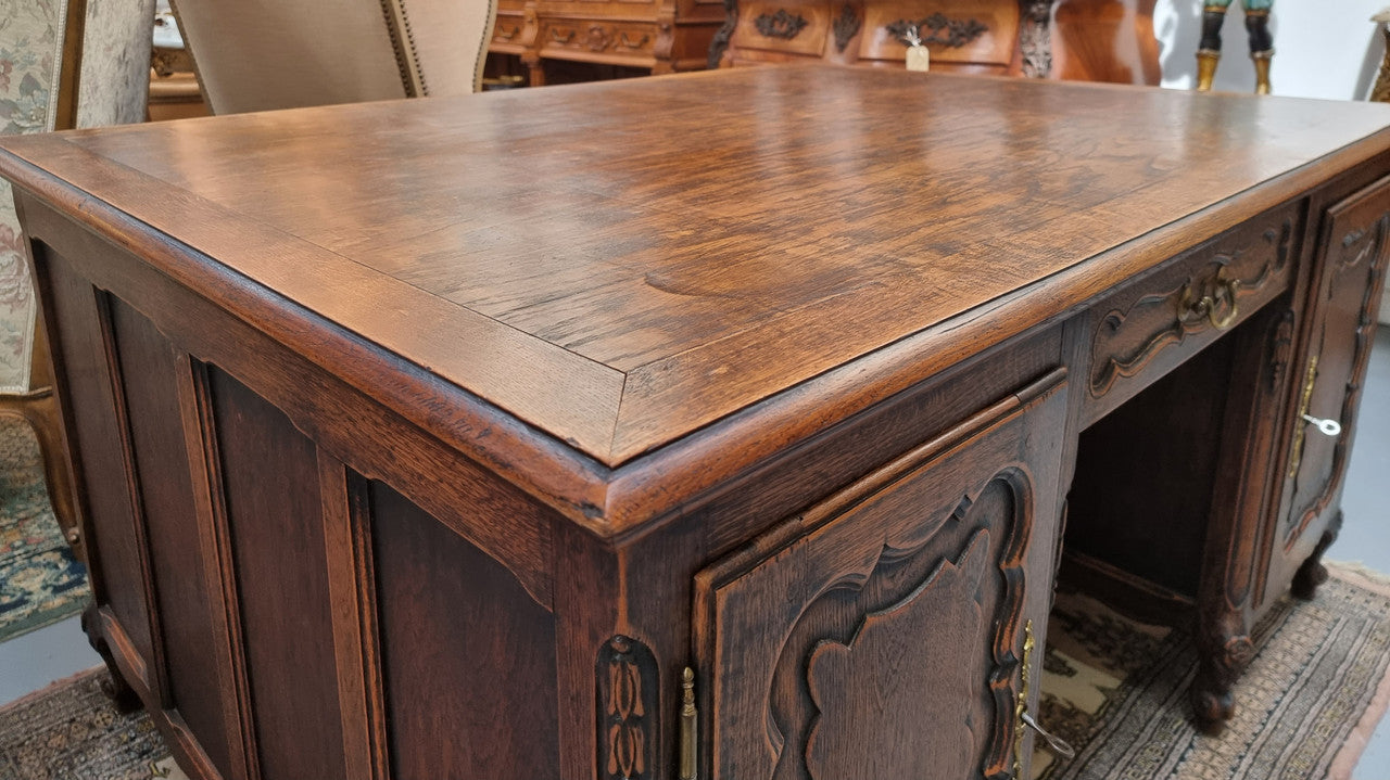 Fabulous Louis XV style French Oak beautifully carved full partners desk. Both sides have a functioning drawer in the middle and two cupboards either side. On both sides one cupboard door opens up to four smaller internal drawers. Plenty of storage space and a large top surface to work on. It is in good original detailed condition.