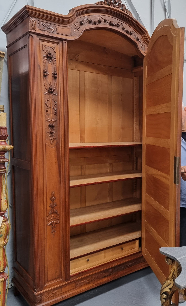 Imposing Louis XV style single mirrored door Walnut armoire. Features deep carved decoration, two interior drawers and three adjustable shelves. It is in good original detailed condition and has been sourced from France.