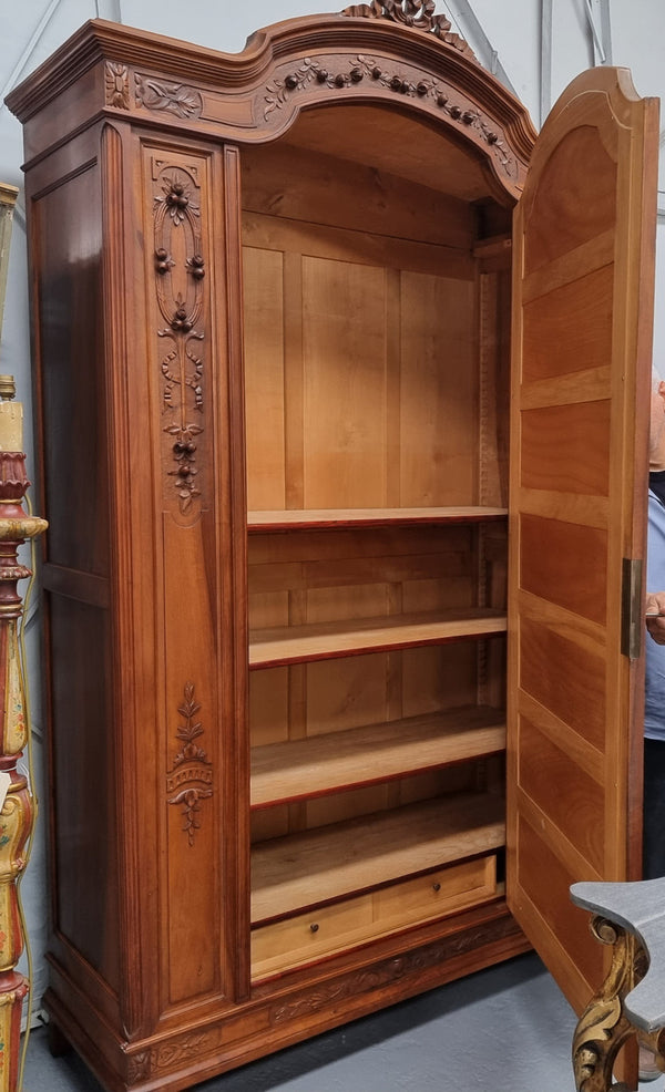 Imposing Louis XV style single mirrored door Walnut armoire. Features deep carved decoration, two interior drawers and three adjustable shelves. It is in good original detailed condition and has been sourced from France.