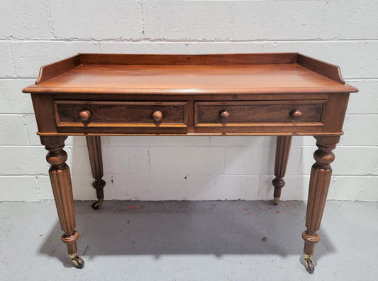 English Victorian Mahogany side table or desk with two drawers and gallery, fluted legs and ceramic castors. In good original condition.