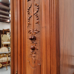 Imposing Louis XV style single mirrored door Walnut armoire. Features deep carved decoration, two interior drawers and three adjustable shelves. It is in good original detailed condition and has been sourced from France.