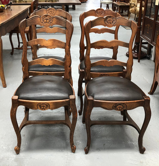 A set of four French Louis XV style, ladder back oak chairs. With finely carved detail and newly upholstered leather look seat. In great original condition. Chairs are comfortable and sturdy for everyday use.