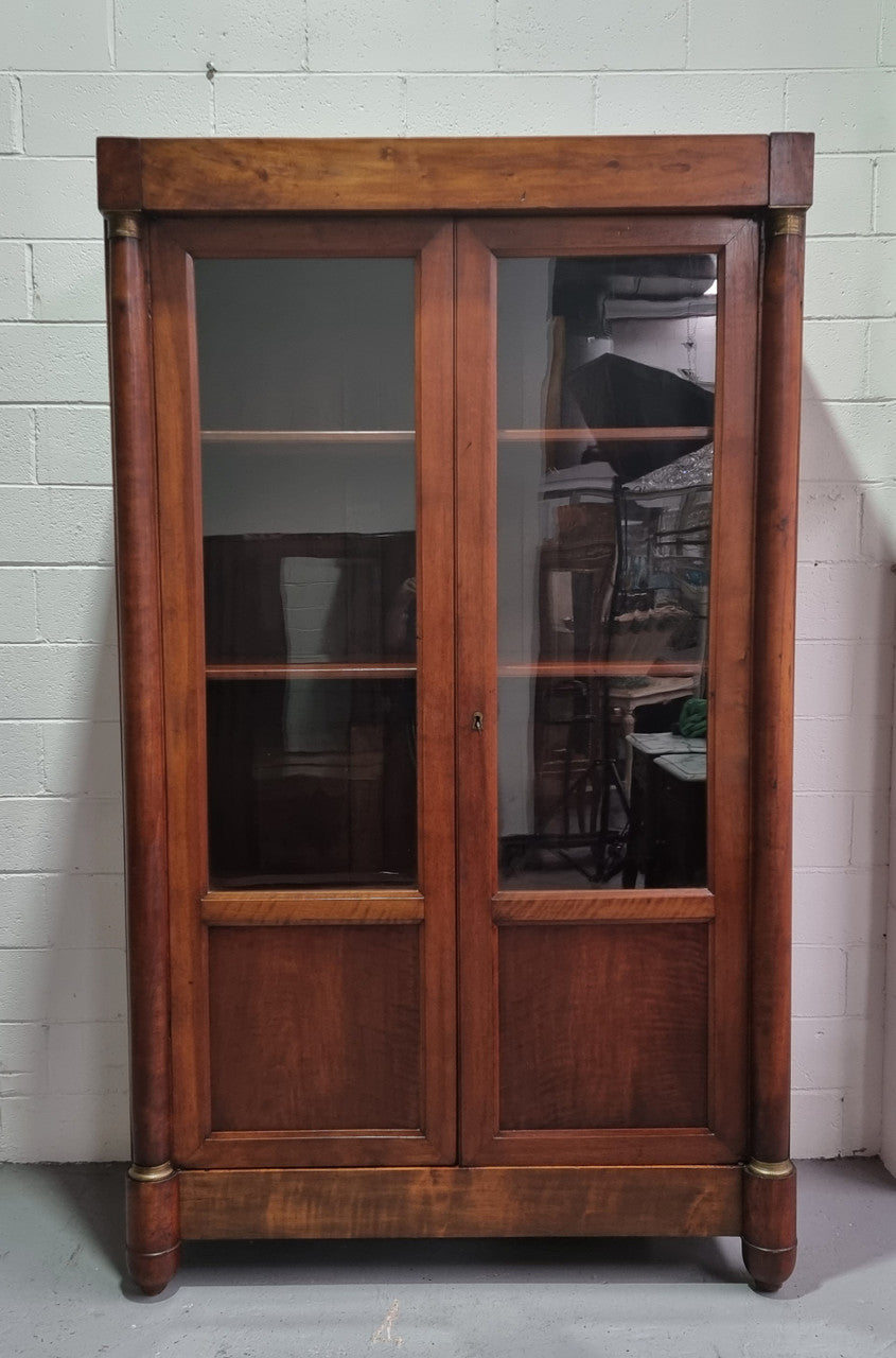 Grand French Mahogany Empire two door bookcase. It has beautiful glass doors and has three fully adjustable shelves. It has been sourced from France and is in good original detailed condition.