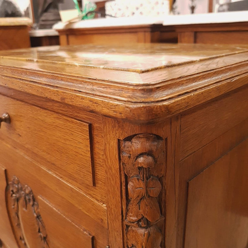 A French oak single bedside cabinet, with a marble inset top, finely carved detail, cupboard space and a drawer. In good original condition.