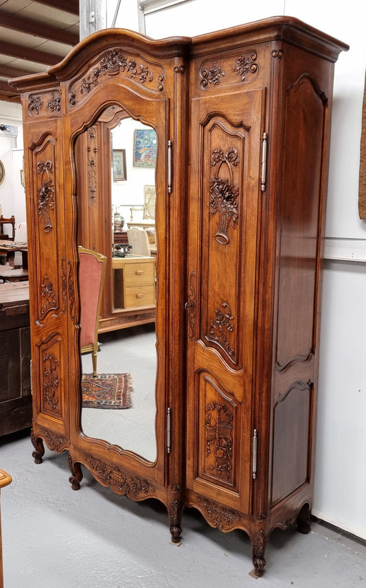 French Walnut Louis XV style three door armoire with 10 fully adjustable shelves in total spread over three sections, two drawers and a mirrored middle door. It has been sourced from France and in good original detailed condition.