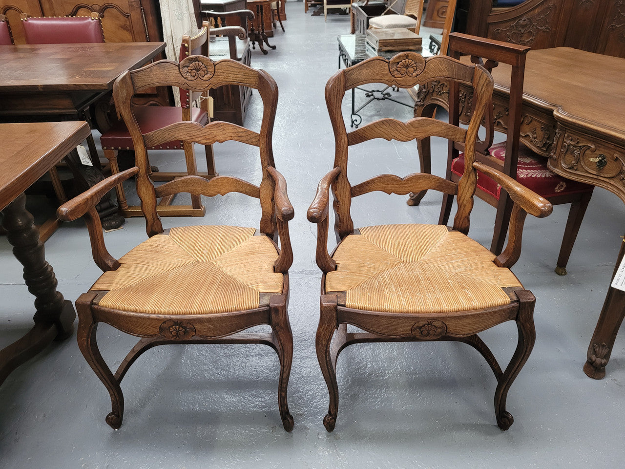Pair of Louis XV Style Oak framed rush seated carver chairs. They have been sourced from France and in good original detailed condition.
