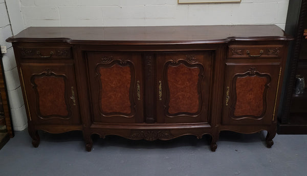 Fabulous Louis XV style French Walnut and Burr Walnut four door sideboard. Each door panel has beautiful Burr Walnut panels and open up to an adjustable shelf. Beautiful handles and two drawers for added storage. In good original detailed condition.