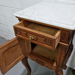 Lovely pair of French Oak carved Louis XV style bedside cabinets with a white marble top, drawer and cupboard in good original detailed condition.