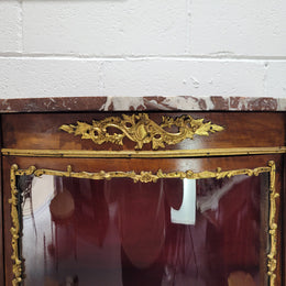 Louis XV style Vitrine with curved glass and red velvet lining. It has two fixed shelves with a marble top and ormolu decoration. In good original detailed condition.