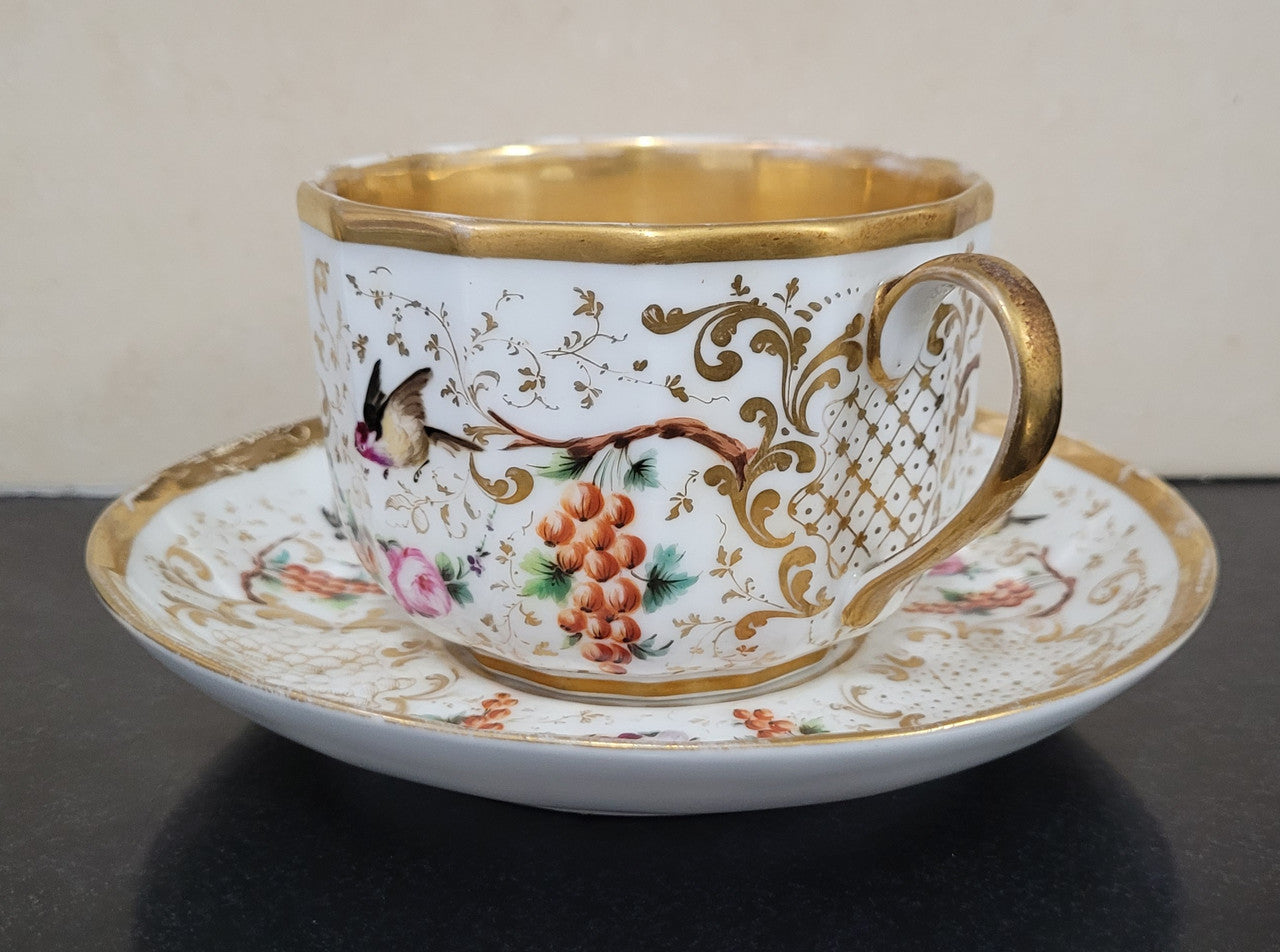 “Old Paris Porcelain” large cup and saucer, beautifully decorated with birds, grapes, floral sprays and heavily gilded. Dated to base 1835. In good original condition please view photos as they help form part of description.