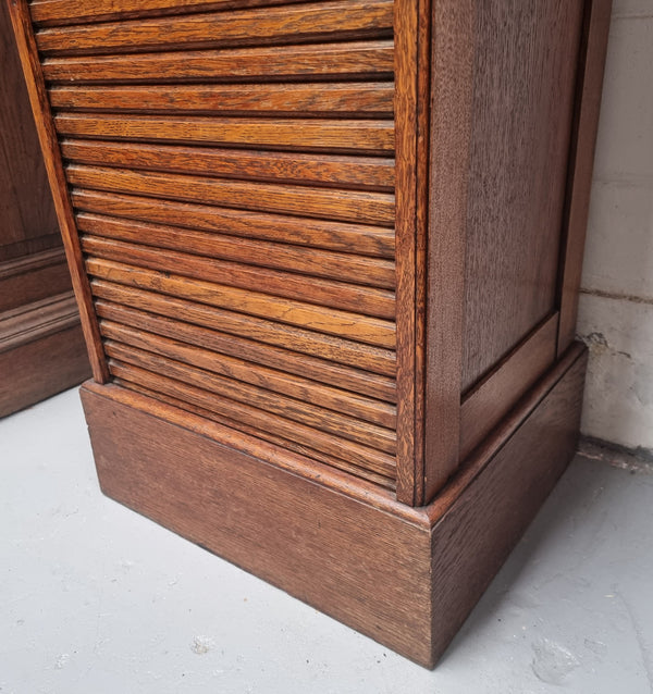 Antique Edwardian roll top Tambour file cabinet desk. This practical antique tambour front filing cabinet dates around 1900 in the Edwardian period and is constructed from Oak. This antique cabinet has an adjustable writing slope, above a tambour front with key and working lock. It has been sourced locally and is in good original detailed condition.