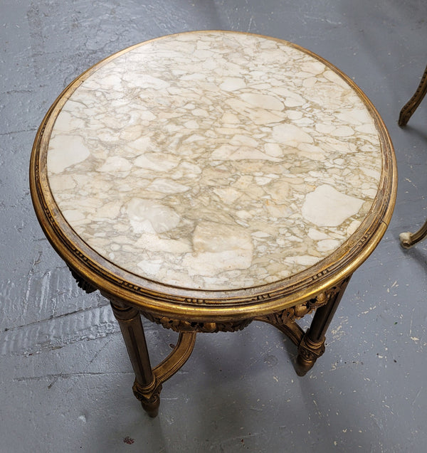 French Louis XVI style round marble topped gilded lamp/side table featuring lovely carved swags and undercarriage. It has been sourced from France and is in good original detailed condition.