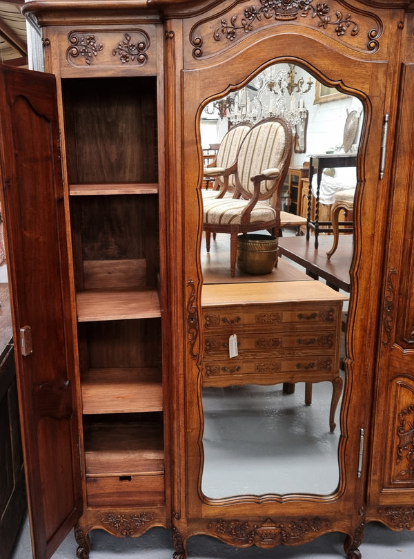 French Walnut Louis XV style three door armoire with 10 fully adjustable shelves in total spread over three sections, two drawers and a mirrored middle door. It has been sourced from France and in good original detailed condition.