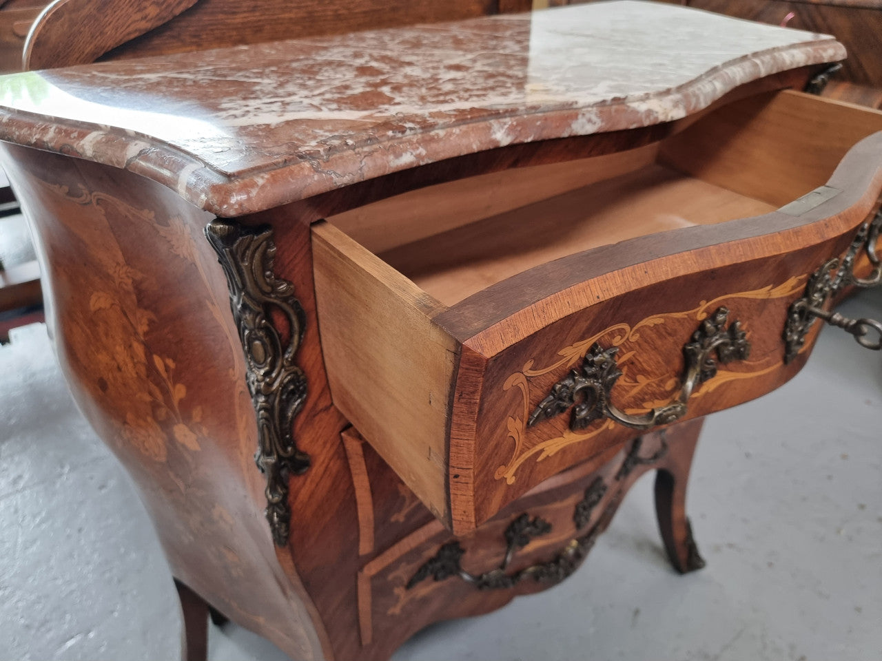 Antique French Louis XV style compact three drawer marble top commode with marquetry inlay and ormolu mounts. Sourced from France and in good original detailed condition.