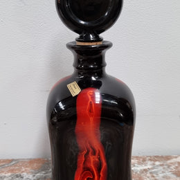 Vintage Designer glass carafe by “Stromit Handarbeit”.  Dark background with flashes of orange/red.