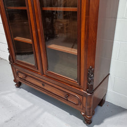 Antique Mahogany two door Biedermeier style bookcase with four fully adjustable shelves and a drawer at the bottom. The two wooden finials at the top are easily removed for a different look of desired. In good original detailed condition.