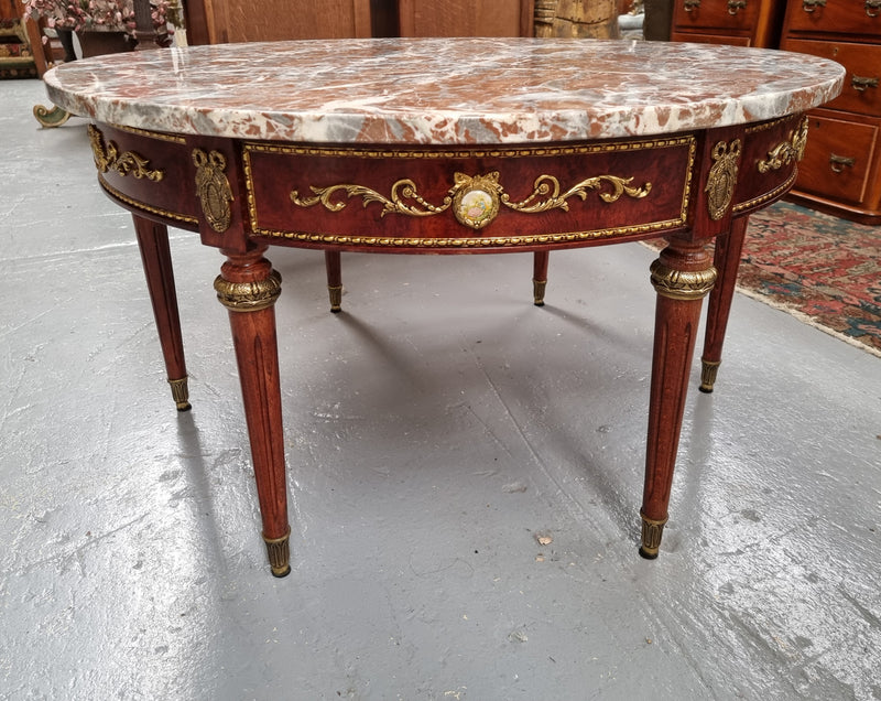 Stunning Antique French style Burr Walnut marble top coffee table. It has gilt metal mounts all around the top edge, with more down the fluted legs & feet. It also has exquisite painted porcelain plaques encased in gilt metal laurel wreaths all around the top edge. It is also stamped underneath "Muarva S.L. Made In Spain". It is in good original detailed condition.