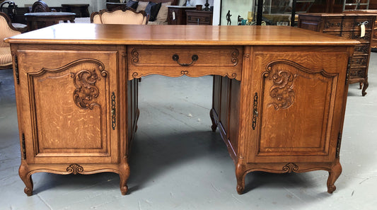 Lovely French oak carved partners desk with one drawer and two cupboards on each side for all your storage needs. in good original detailed condition.